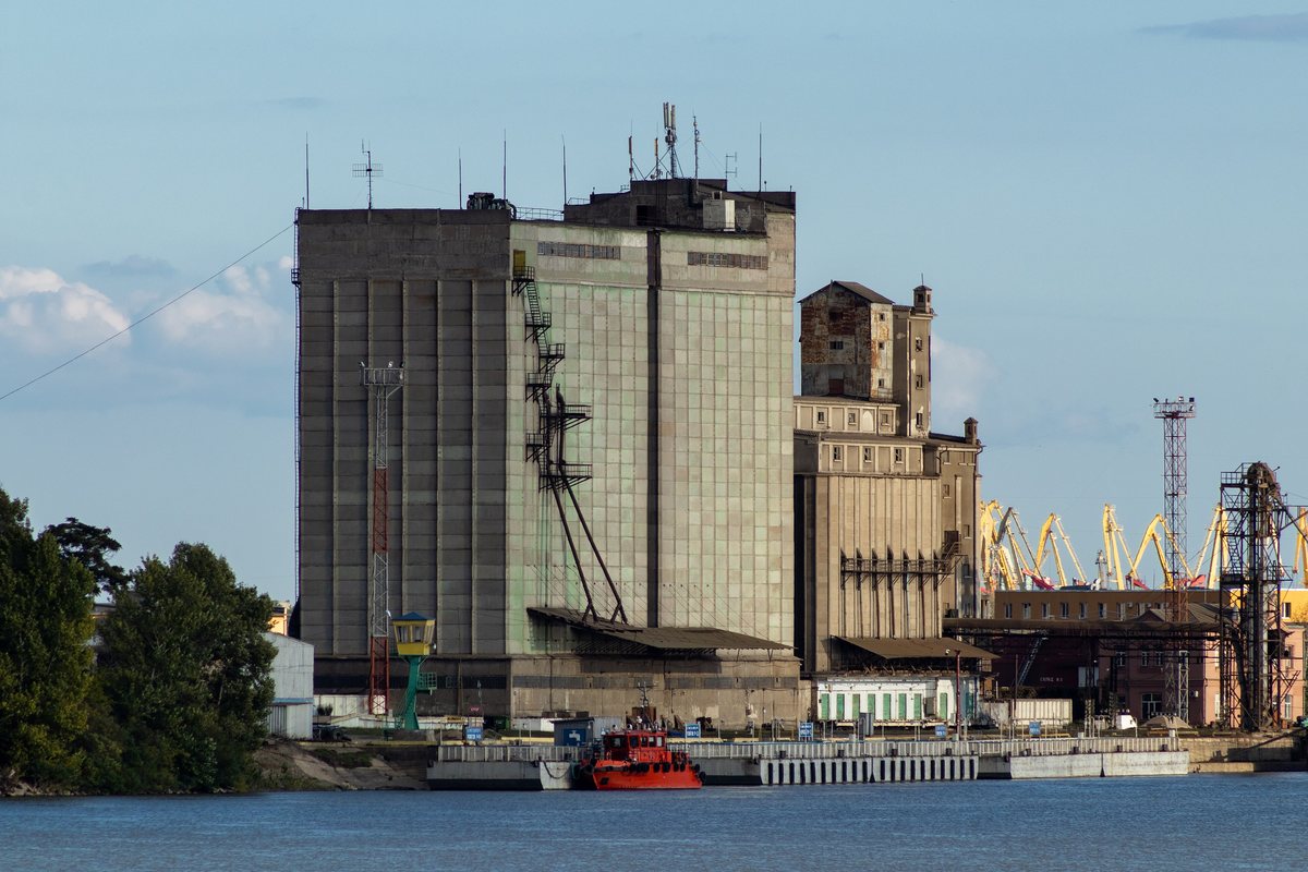 Elevador de grãos de concreto no porto fluvial de Izmail, no Danúbio, com guindastes ao fundo